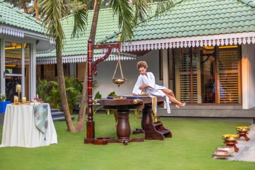 a man sitting on a swing with a table at Heritage Village Resort & Spa Goa in Cansaulim