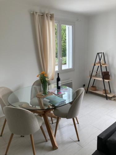Un comedor con una mesa de cristal y sillas. en Charmante villa à istres, en Istres
