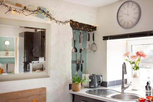 a kitchen with a sink and a clock on the wall at Friday Cottage - Brixham in Brixham