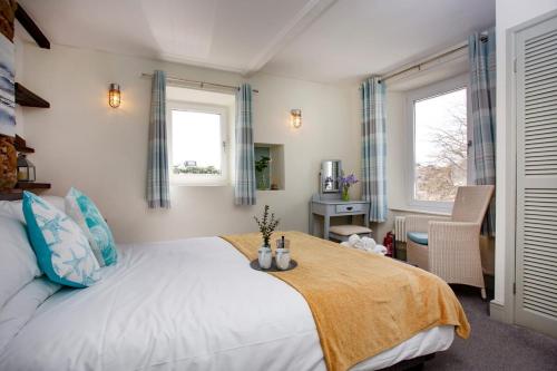 a bedroom with a large bed and two windows at Friday Cottage - Brixham in Brixham