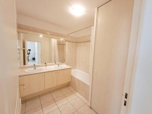 une salle de bain avec un lavabo, une baignoire et un miroir dans l'établissement Grand T3 avec Terrasse et Jardin, à Fréjus