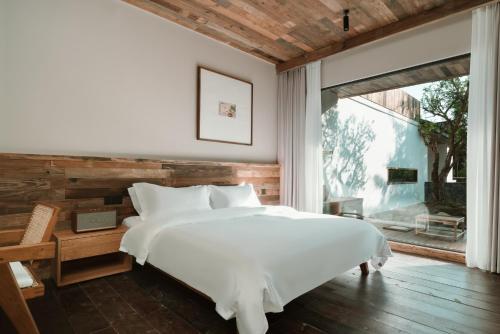 a bedroom with a white bed and a large window at YunXi ChanYi Hot Spring Hotel in Emeishan