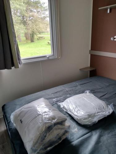 due sacchetti di plastica appoggiati su un letto accanto a una finestra di Mobil Home a Montaigu-Vendée