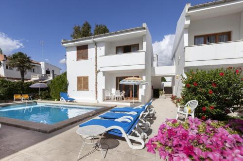 a villa with a swimming pool and lounge chairs at Apartamentos Leo in Port de Pollensa