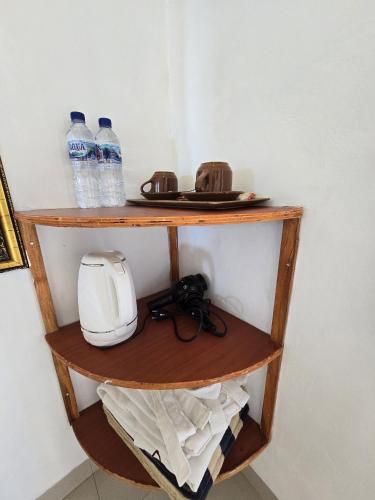 a shelf with bottles of water and a toaster at Kelingking BMS Penida Hills Villa in Nusa Penida