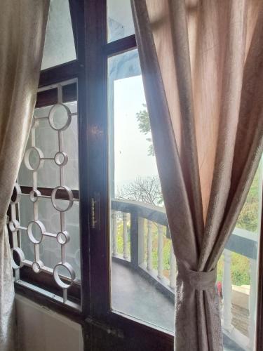 an open window with a view of a balcony at Hotel Sakura Mountain view Near Darjeeling Toy Train Station in Darjeeling