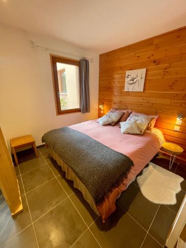 une chambre avec un grand lit avec un mur en bois dans l'établissement GITES ROC N' VOL AU COEUR DU VERDON, à La Palud-sur-Verdon