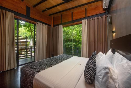 a bedroom with a bed and a large window at Atha Resort in Sigiriya