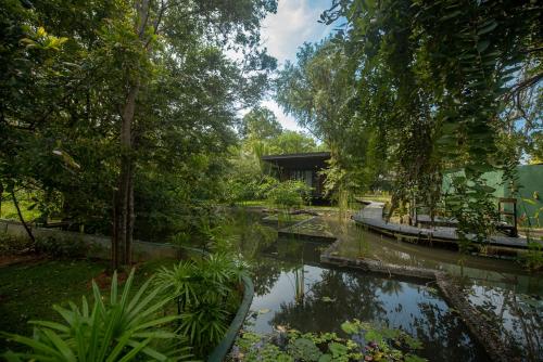 a garden with a pond and trees and a building at Atha Resort in Sigiriya