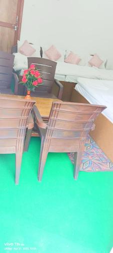 a table and chair with a vase of flowers on it at Hotel Prakriti Darshan in Bhatwāri