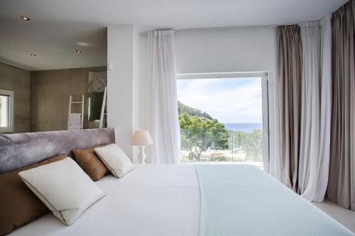 サン・ジョセップ・デ・サ・タライアにあるVilla Sargantanaの大きなベッドと大きな窓のある寝室