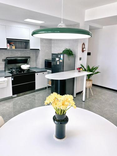 Una cocina con una mesa blanca y un jarrón de flores amarillas. en Jianshui Our Home Art B&B, en Jianshui