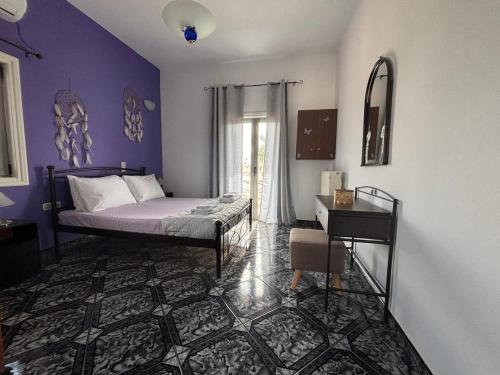 a bedroom with a bed with purple walls and a table at Arena's Place in Tympáki