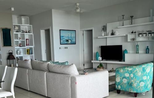 a living room with a couch and a tv at Salineo II Penthouse in Tamarin