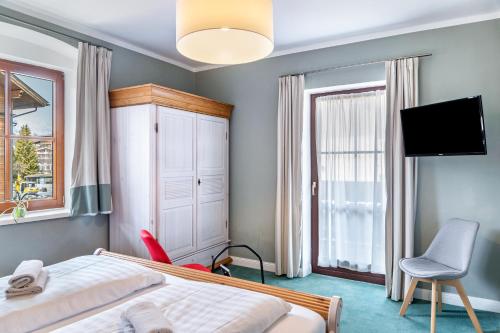 a bedroom with a bed and a tv and a chair at Chalet Sonneck - Seefeld in Seefeld in Tirol
