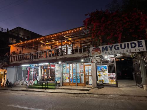 a building with a sign on the side of a street at MyGuide Travellers Inn in Coron