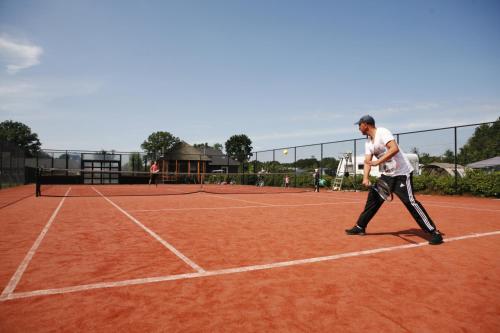 a man playing tennis on a tennis court at Wander Lodge 5 persons in Voorthuizen