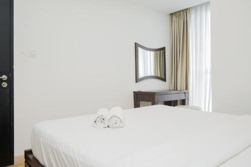 a bedroom with a large white bed and a mirror at Comfort 1BR at Branz BSD Apartment By Travelio in Tangerang