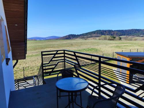 a balcony with a table and chairs and a field at Apartament Widokówka in Hoczew