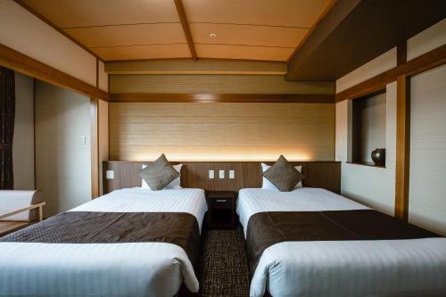 two beds in a room with wooden walls at KAMENOI HOTEL Kochi in Ino