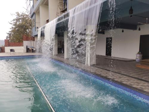 a swimming pool with a water fountain at Nisarga Lake Resort Tapola in Satara