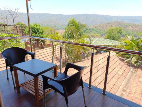 a balcony with two chairs and a table and a view at Nisarga Lake Resort Tapola in Satara