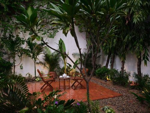 a garden with two chairs and a table and trees at juSTa Diwans Bungalow in Ahmedabad