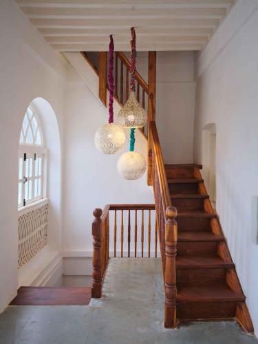a hallway with a staircase with chandeliers at juSTa Diwans Bungalow in Ahmedabad