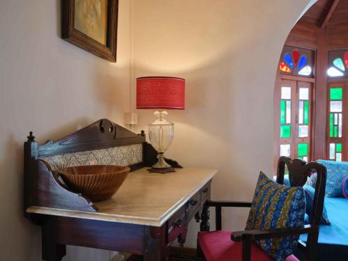 a room with a table with a lamp and a chair at juSTa Diwans Bungalow in Ahmedabad