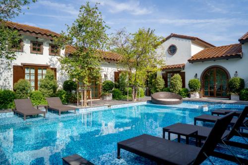 a swimming pool with chairs in front of a house at Villa Seville in Hua Hin