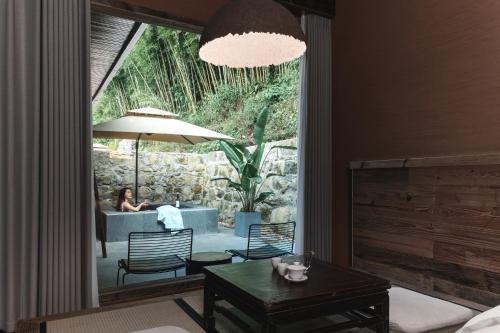 a room with a table and a woman sitting in a couch at YunXi ChanYi Hot Spring Hotel in Emeishan
