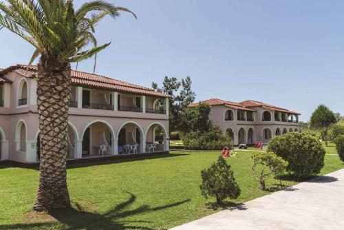 a palm tree in front of a house at Kamari Apartments in Litherés