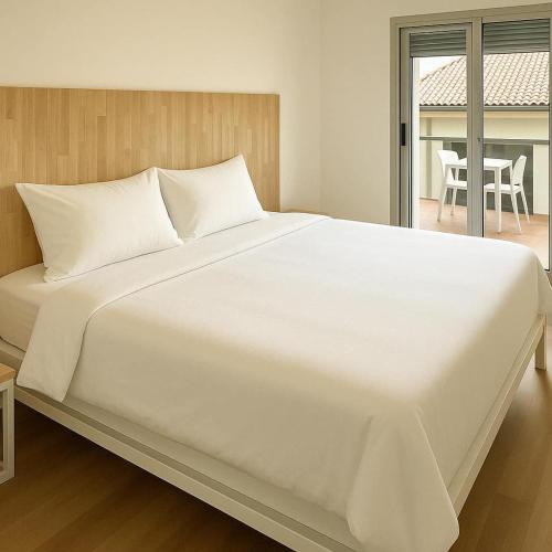 Cette chambre comprend un grand lit blanc et une table. dans l'établissement Le Moderne à Nîmes, proche Arènes et gare, à Nîmes