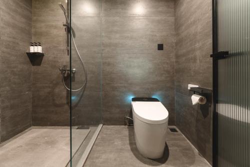 a bathroom with a toilet and a glass shower at YunXi ChanYi Hot Spring Hotel in Emeishan