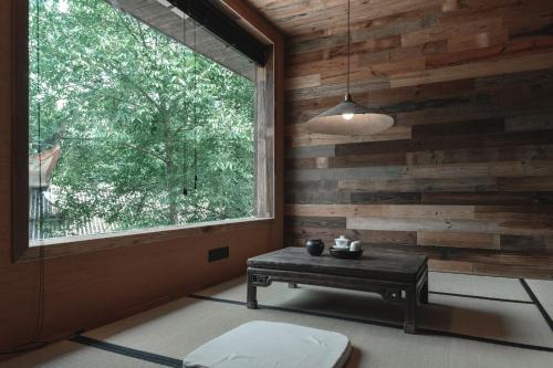 a room with a table and a large window at YunXi ChanYi Hot Spring Hotel in Emeishan