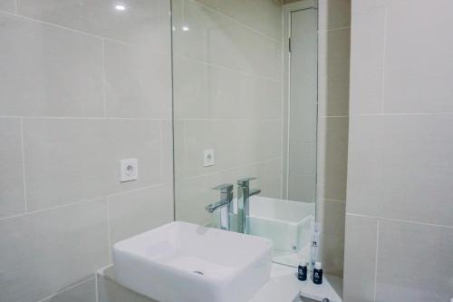 a white bathroom with a sink and a mirror at Pleasurable and Tidy Studio Daan Mogot City Apartment By Travelio in Jakarta