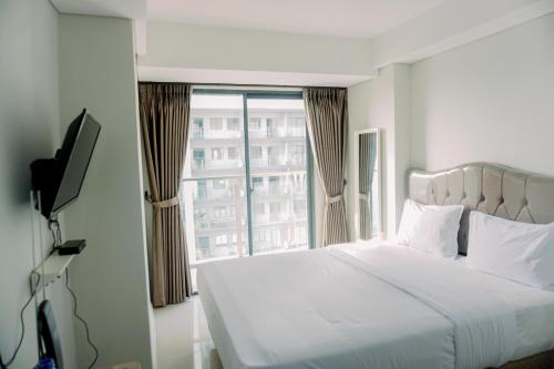a bedroom with a bed and a large window at Pleasurable and Tidy Studio Daan Mogot City Apartment By Travelio in Jakarta