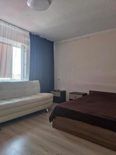 a bedroom with a bed and a couch and a window at Elite Capsule Hotel in Balqash