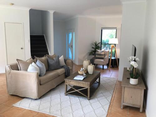 Una sala de estar con un sofá y una mesa de café. en Luxury 3 bedroom townhouse, stroll to beaches, en Shelly Beach