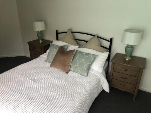 1 dormitorio con 1 cama con almohadas y 2 mesitas de noche en Luxury 3 bedroom townhouse, stroll to beaches, en Shelly Beach