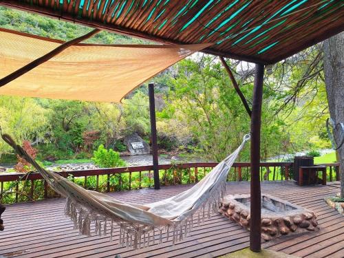 a hammock on a deck with a tree at Unit Blessed in Oudtshoorn