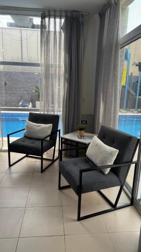two chairs and a table in a room with a pool at Natalie water park chalet in Al Kafrayn