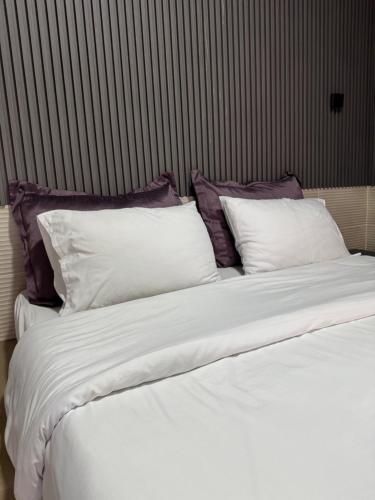 a large bed with white sheets and purple pillows at Natalie water park chalet in Al Kafrayn