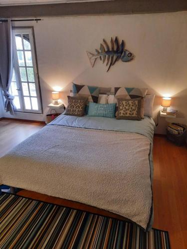 - une chambre avec un lit avec un poisson sur le mur dans l'établissement La paillote des Ninous, à Bassan