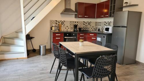 une cuisine avec une table avec des chaises et un réfrigérateur dans l'établissement Gîte Bambou, Beauval Zoo, à Seigy