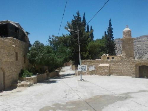 a stone building with a sign in front of it at Wadi Dana Lodge - نزل وادي ضانا in Dana