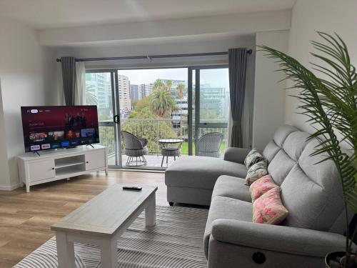 a living room with a couch and a tv at Penthouse Delight 3 bd 2 bth free carpark, pool & tennis court in Auckland