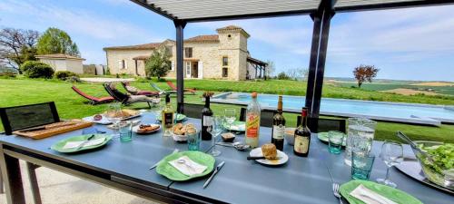 een tafel met eten en flessen wijn erop bij La Colline Gersoise-Piscine-Sauna in La Sauvetat