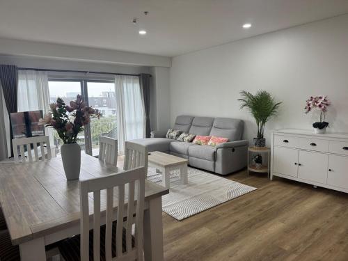 a living room with a couch and a table at Penthouse Delight 3 bd 2 bth free carpark, pool & tennis court in Auckland
