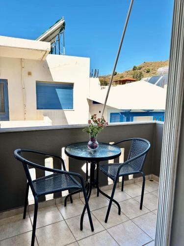a table and chairs on a balcony with a vase of flowers at ''Studios Anna'' in Léntas